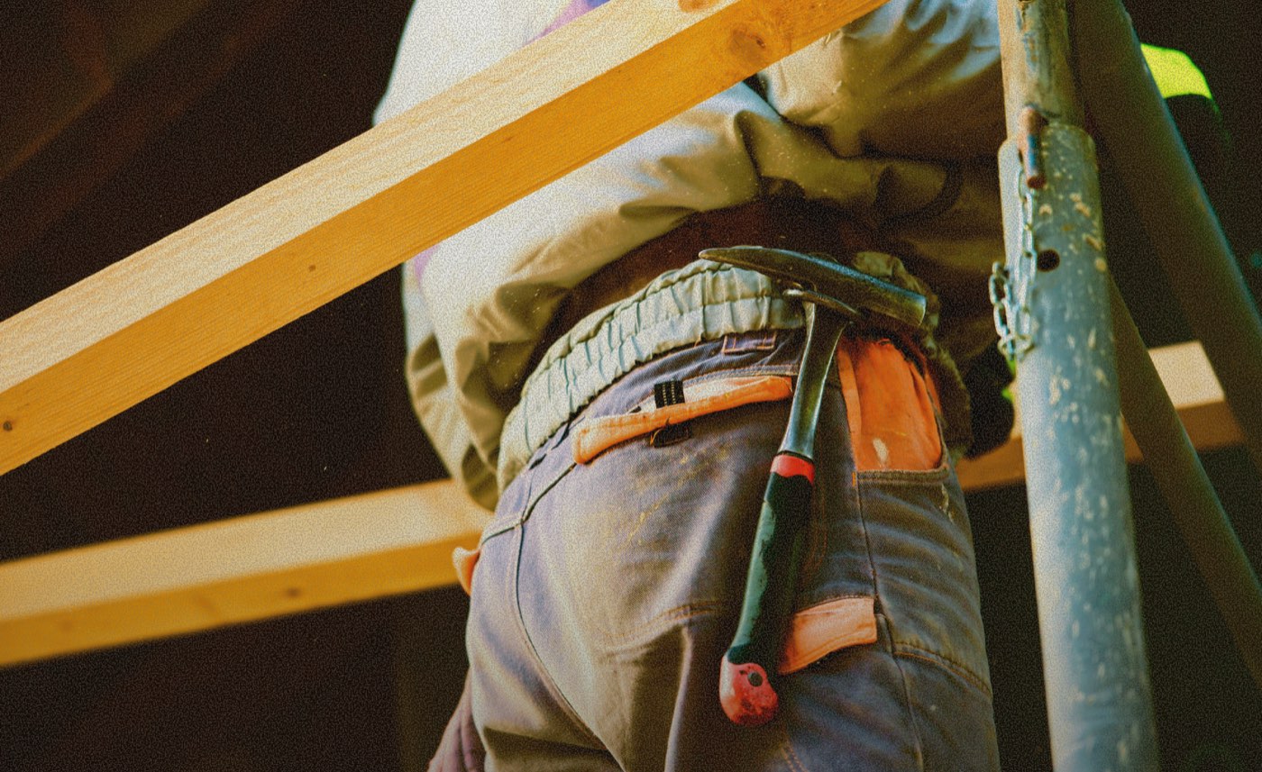 Roofer's tool belt with a hammer, framed by lumber